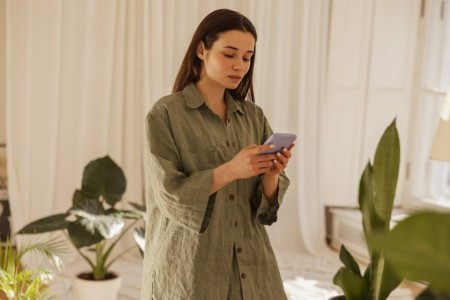 calm-young-caucasian-woman-looks-screen-mobile-phone-her-hands-indoors-brunette-long-green-shirt-reads-sms-social-network-technological-device-concept.jpg