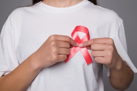 woman wearing white t-shirt holding pink cancer ribbon